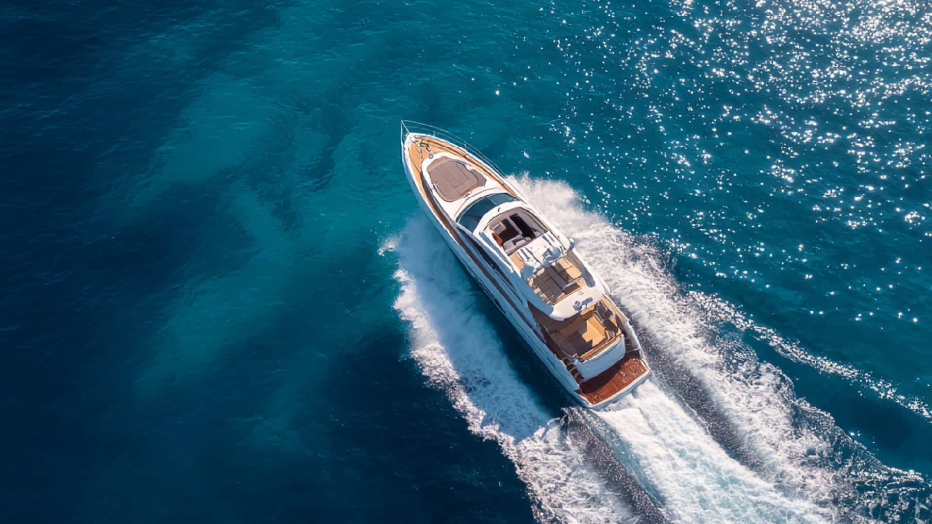 Superyacht anchored inside a Maldivian atoll — turquoise lagoon water with the coral reef ring visible beyond